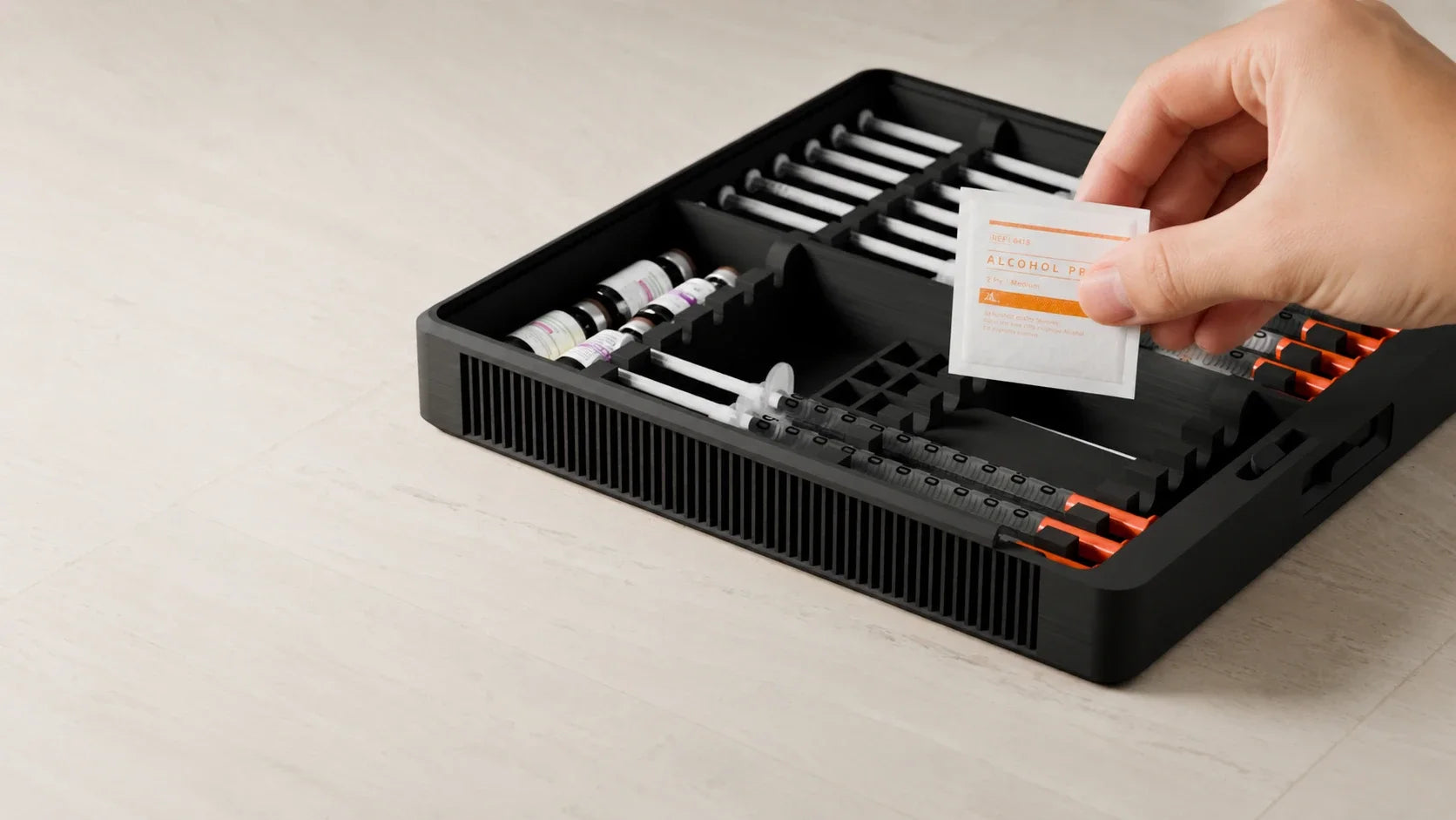 Hand holding an alcohol prep pad above the organized Routine Box